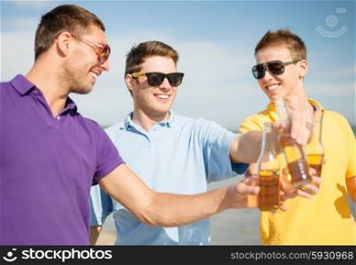 summer holidays, vacation, people and bachelor party concept - group of happy male friends having fun and drinking beer on beach
