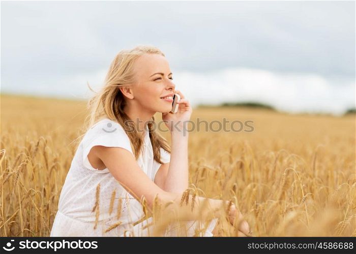 summer holidays, vacation, technology and people concept - smiling young woman in white dress calling on smartphone on cereal field