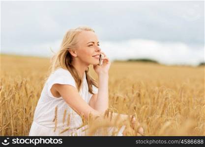 summer holidays, vacation, technology and people concept - smiling young woman in white dress calling on smartphone on cereal field