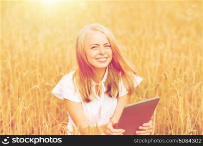 summer holidays, vacation, technology and people concept - smiling young woman in white dress with tablet pc computer on cereal field. happy young woman with tablet pc on cereal field. happy young woman with tablet pc on cereal field