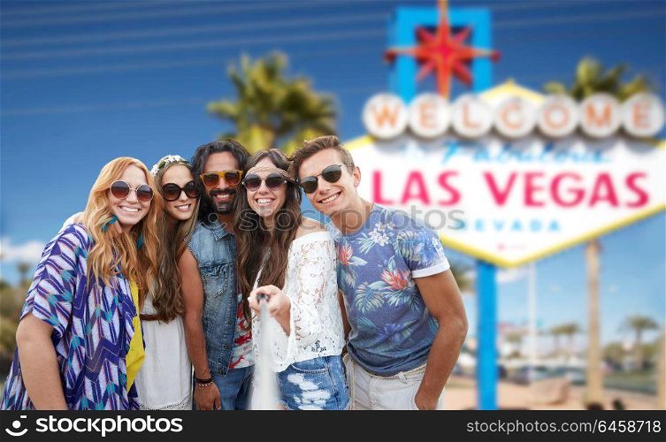 summer holidays, vacation, tourism and travel concept - group of smiling hippie friends taking selfie by smartphone over welcome to fabulous las vegas sign background. friends travelling to las vegas and taking selfie