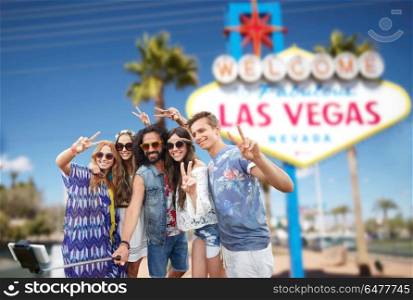 summer holidays, vacation, tourism and travel concept - group of smiling hippie friends taking selfie by smartphone and showing peace over welcome to fabulous las vegas sign background. friends travelling to las vegas and taking selfie. friends travelling to las vegas and taking selfie