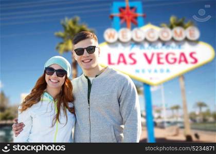 summer holidays, vacation, tourism and travel concept - happy teenage couple in shades over welcome to fabulous las vegas sign background. teenage couple in shades over las vegas sign