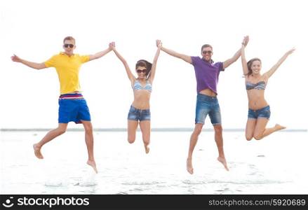 summer holidays, vacation, tourism, travel and people concept - group of happy friends holding hands and jumping on beach