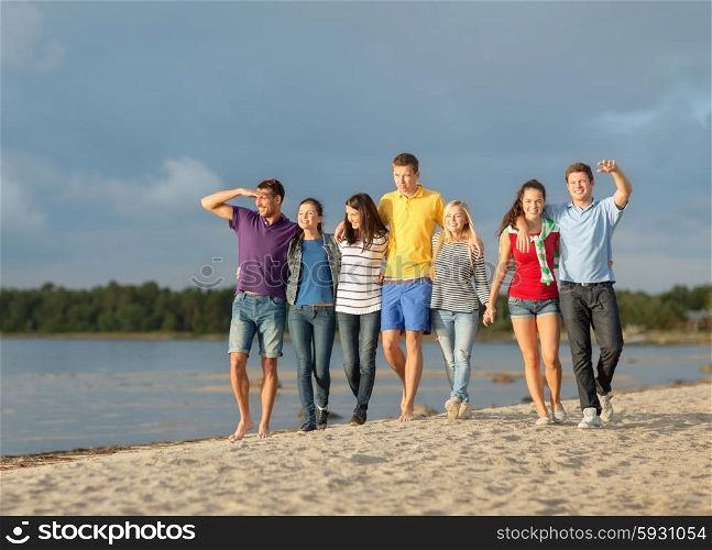 summer holidays, vacation, tourism, travel and people concept - group of happy friends pointing finger and walking along beach