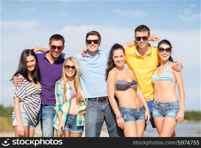 summer holidays, vacation, tourism, travel and people concept - group of happy friends in sunglasses hugging on beach