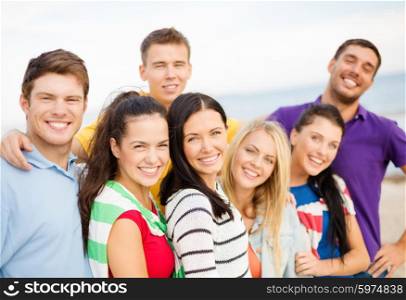 summer holidays, vacation, tourism, travel and people concept - group of happy friends hugging on beach