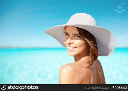 summer holidays, vacation, travel and people concept - smiling young woman in sun hat on beach over sea and blue sky background. smiling young woman in sun hat on summer beach