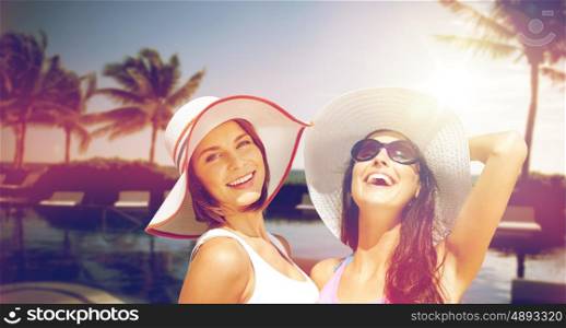 summer holidays, vacation, travel and people concept - smiling young women in hats and casual clothes on beach