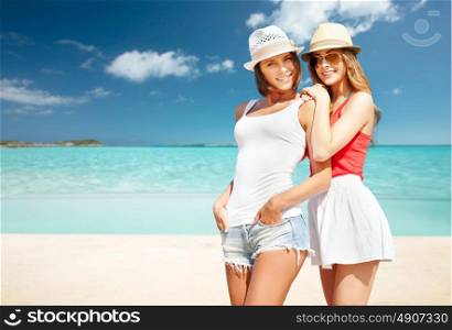 summer holidays, vacation, travel and people concept - smiling young women in hats and casual clothes over exotic tropical beach background. smiling young women in hats on beach