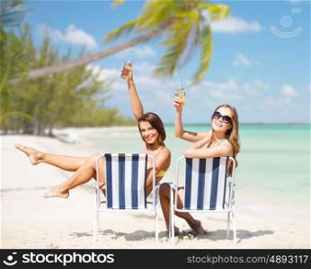 summer holidays, vacation, travel and tourism people concept - smiling young women with drinks sunbathing over exotic tropical beach with palm trees and sea shore background