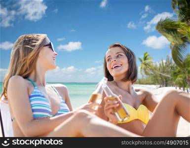 summer holidays, vacation, travel and tourism people concept - smiling young women with drinks sunbathing over exotic tropical beach background. happy young women with drinks sunbathing on beach