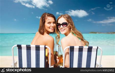 summer holidays, vacation, travel and tourism people concept - smiling young women with drinks sunbathing over exotic tropical beach and sea shore background. happy young women with drinks sunbathing on beach