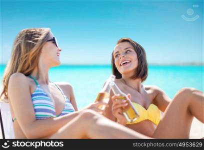 summer holidays, vacation, travel and tourism people concept - smiling young women with drinks sunbathing on beach over sea and blue sky background. happy young women with drinks sunbathing on beach
