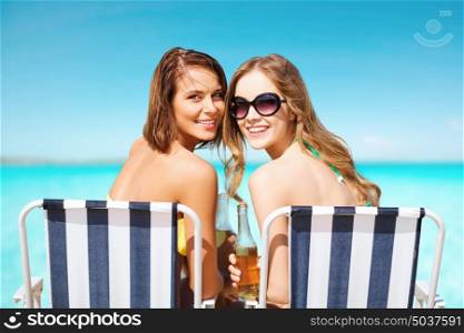 summer holidays, vacation, travel and tourism people concept - smiling young women with drinks sunbathing on beach over blue sky and sea background. happy young women with drinks sunbathing on beach