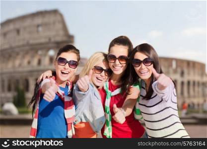 summer holidays, vacation, travel, friendship and people concept - happy teenage girls or young women in sunglasses showing thumbs up and laughing over coliseum background