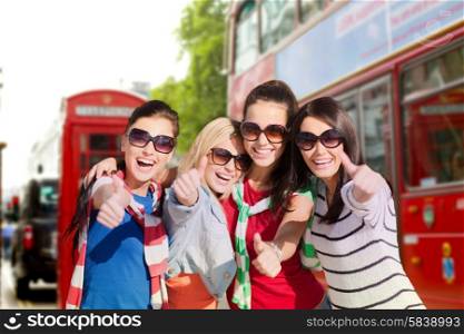 summer holidays, vacation, travel, friendship and people concept - happy teenage girls or young women in sunglasses showing thumbs up and laughing over london city street background