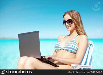summer holidays, vacation, travel, technology and people concept - smiling women in sunglasses with laptop computer sunbathing in lounge over exotic tropical beach background