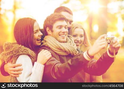 summer, holidays, vacation, travel, tourism, happy people concept - group of friends or couples having fun with photo camera in autumn park