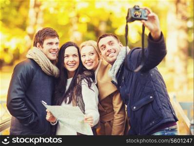 summer, holidays, vacation, travel, tourism, happy people concept - group of friends or couples having fun with photo camera in autumn park