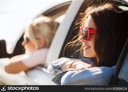 summer holidays, valentines day, travel, road trip and people concept - happy teenage girls or young women heart shaped sunglasses in car at seaside