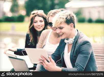 summer, internet, education, campus and teenage concept - group of students or teenagers with laptop and tablet computers hanging out