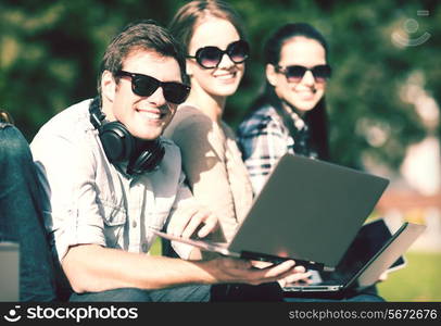 summer, internet, education, campus and teenage concept - group of students or teenagers with laptop and tablet computers hanging out