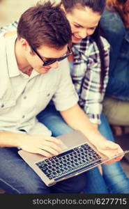 summer, internet, education, campus and teenage concept - students or teenagers with laptop computer hanging out