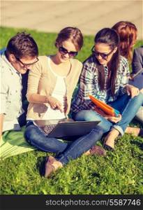 summer, internet, education, technlogy and campus concept - group of students or teenagers with laptop, notebooks and folders