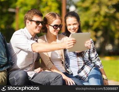 summer, internet, social networking and teenage concept - group of teenagers taking photo with tablet pc outside