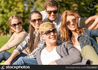 summer, internet, social networking, technology and teenage concept - group of teenagers taking photo with smartphone camera outside