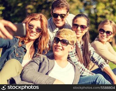 summer, internet, social networking, technology and teenage concept - group of teenagers taking photo with smartphone camera outside