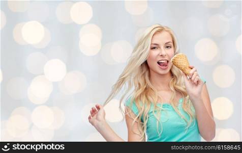 summer, junk food and people concept - young woman in sunglasses eating ice cream over holidays lights background