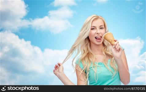 summer, junk food and people concept - young woman in sunglasses eating ice cream over blue sky and clouds background