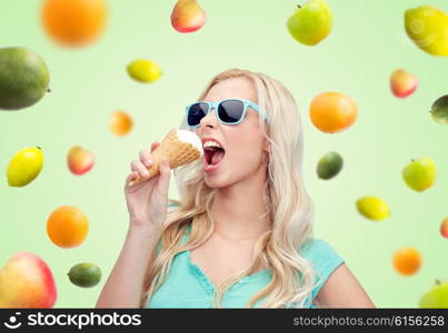 summer, junk food and people concept - young woman or teenage girl in sunglasses eating ice cream over green natural background with fruits