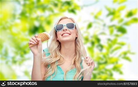 summer, junk food and people concept - young woman or teenage girl in sunglasses eating ice cream over green natural background