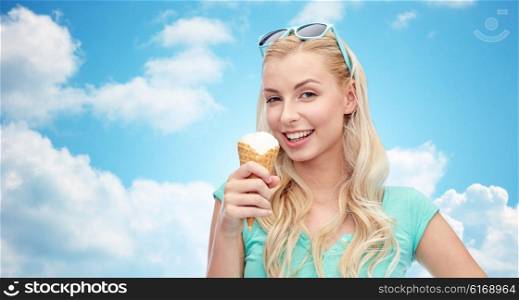 summer, junk food and people concept - young woman or teenage girl in sunglasses eating ice cream over blue sky and clouds background