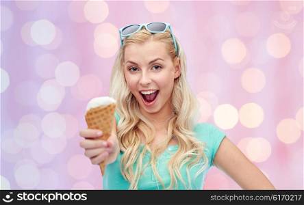 summer, junk food and people concept - young woman or teenage girl in sunglasses eating ice cream over pink holidays lights background