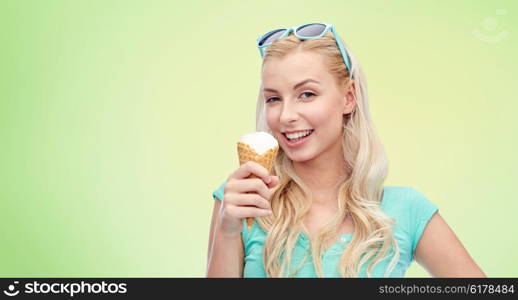 summer, junk food and people concept - young woman or teenage girl in sunglasses eating ice cream over green natural background