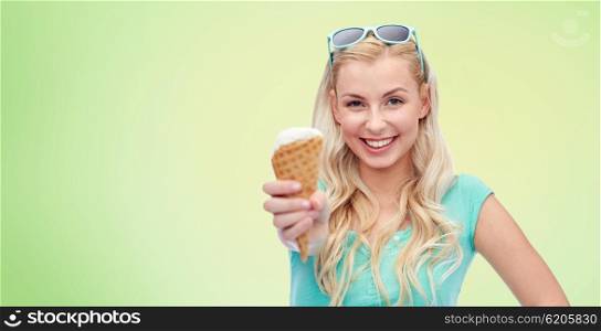 summer, junk food and people concept - young woman or teenage girl in sunglasses eating ice cream over green natural background