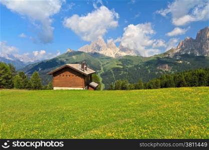 summer landscape in Fassa Valley with a small chalet beneath Dolomites mountains, Trentino, Italy