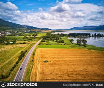 Summer landscape with fields, meadows, lake and mountains. Road on the lakeside. Aerial view of Storage reservoir/lake Hrhovske, Rybniky