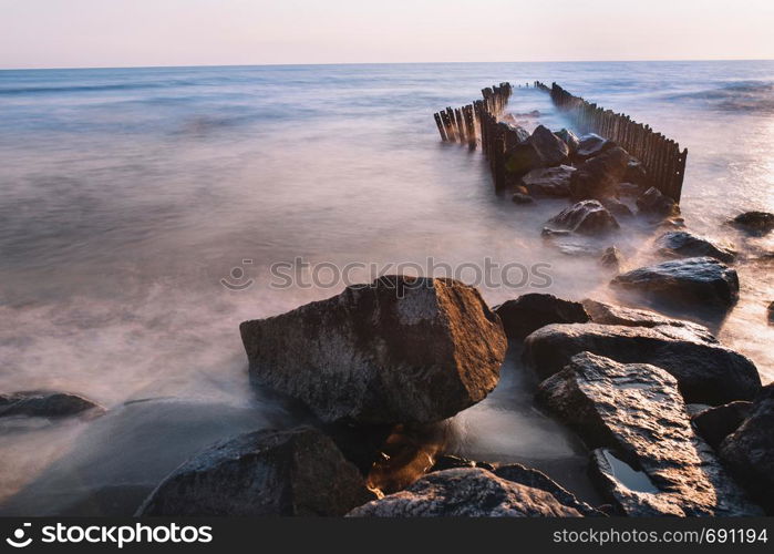 Summer Landscape with Pink sunset Sky on the Sea and stones on the beach. Minimal style construction in to the Sea