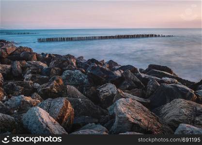 Summer Landscape with Pink sunset Sky on the Sea and stones on the beach. Minimal style construction in to the Sea