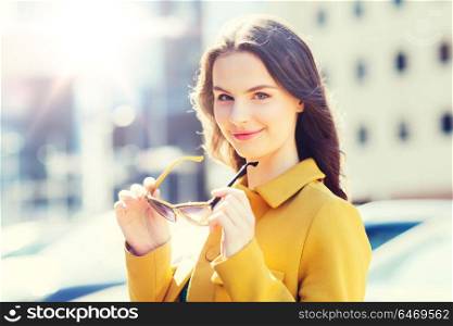summer, leisure, fashion and people concept - smiling young woman with sunglasses in city. smiling young woman with sunglasses in city