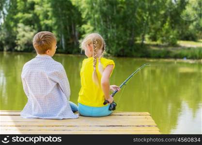 Summer leisure. Rear view of two children sitting at bank and fishing