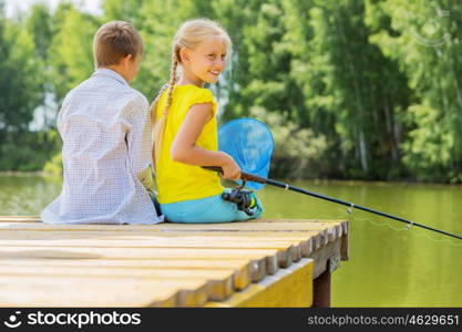 Summer leisure. Rear view of two children sitting at bank and fishing