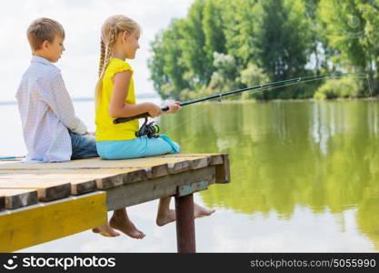 Summer leisure. Rear view of two children sitting at bank and fishing