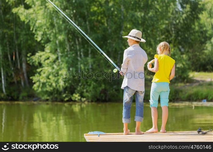 Summer leisure. Rear view of two children standing at bank and fishing
