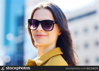 summer, leisure, vacation and people concept - smiling young woman with sunglasses in city